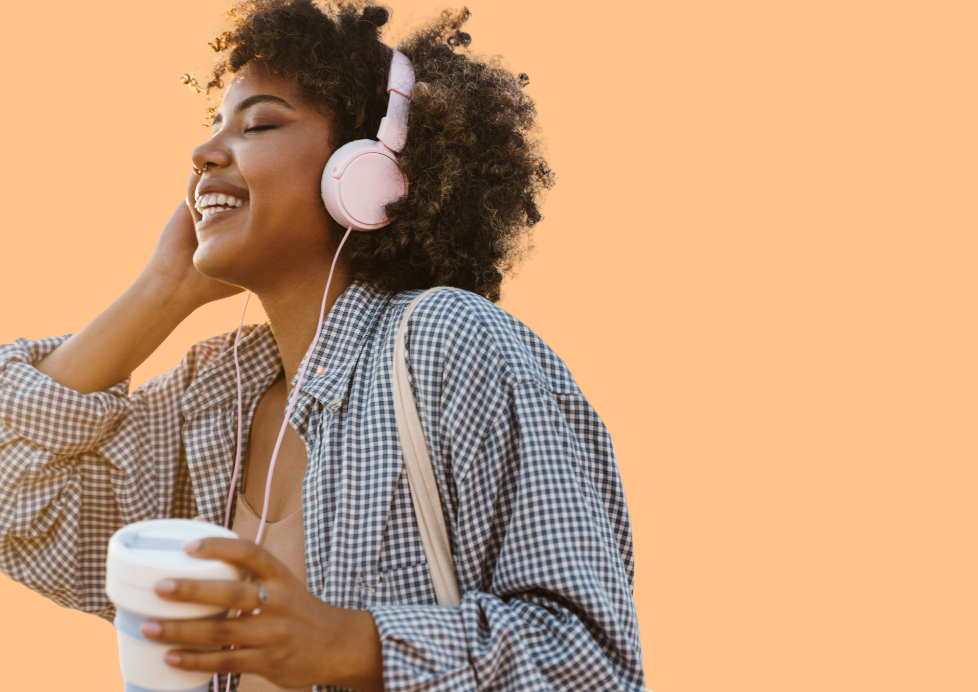 Young woman is listening to music on headphones and smiling. Orange Background.