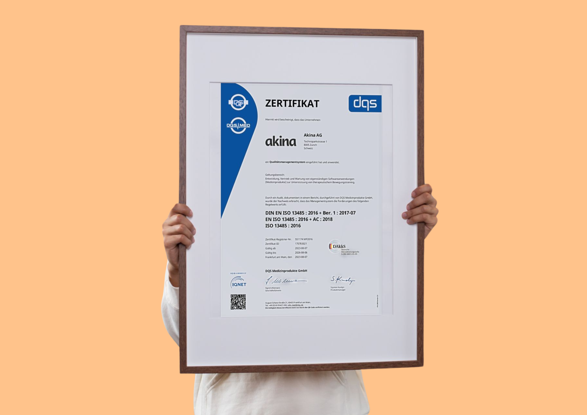 ISO 13485 certificate from Akina, framed. Orange background.