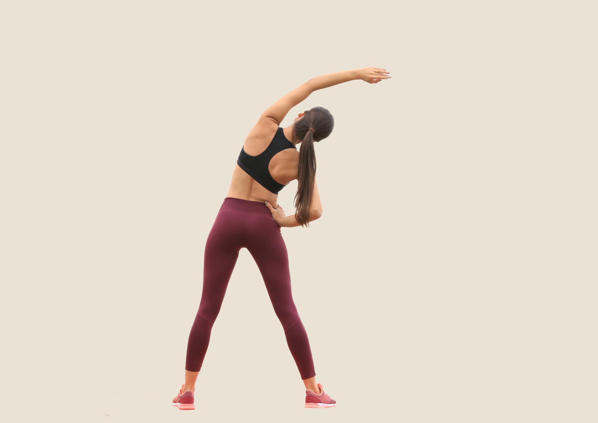 Woman is stretching her back and arms. Beige background.
