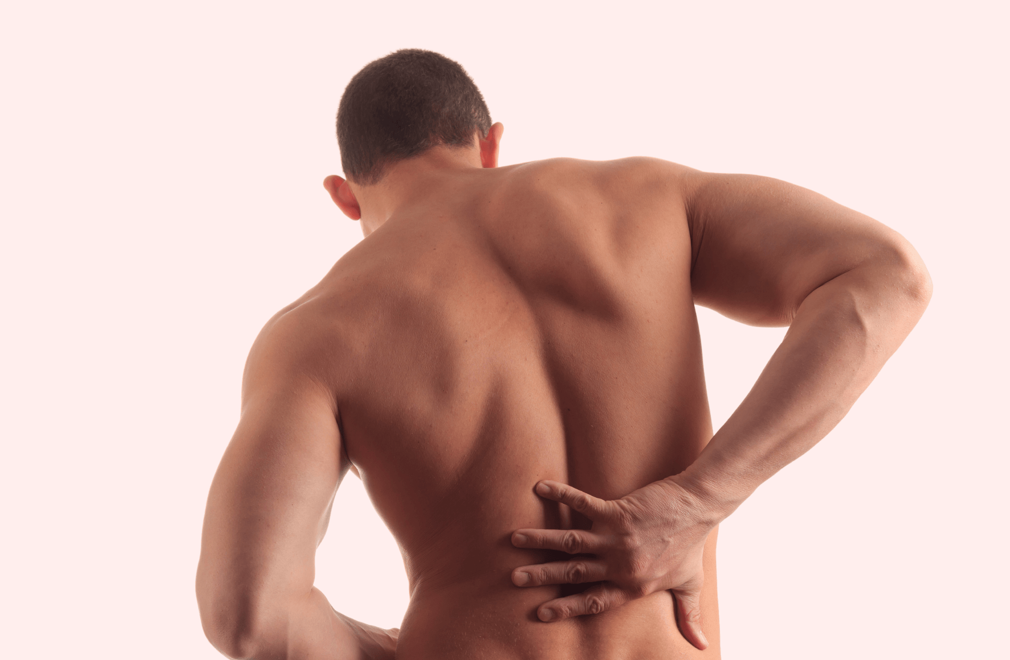 Shirtless man holds on to back because he is in pain.