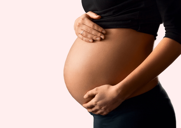 Pregnant woman with hands on her baby bump.